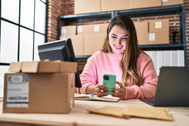 Genç, güzel, İspanyol bir kadın. İş kadını. Ofiste akıllı telefon kullanıyor.