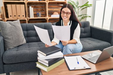Young beautiful hispanic woman psychologist reading document at office