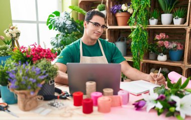 Çiçekçide dizüstü bilgisayar kullanan İspanyol bir çiçekçi.