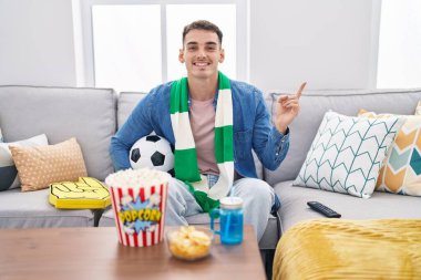 Yakışıklı İspanyol adam topu tutuyor, gülümsüyor, mutlu bir şekilde elini ve parmağını yana uzatıyordu. 