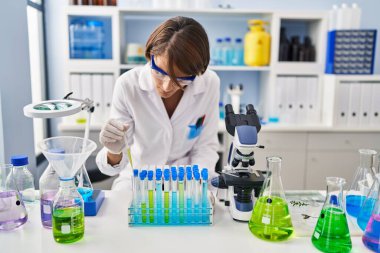 Genç ve güzel İspanyol bilim kadını laboratuardaki test tüplerine sıvı döküyor.