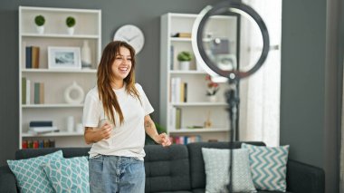 Genç, güzel, İspanyol bir kadın gülümsüyor. Kendine güvenen, evde dans eden, kendine güvenen.