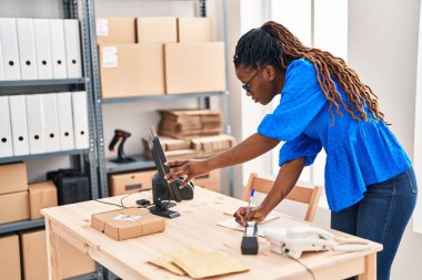 African american woman ecommerce business worker writing on notebook at street