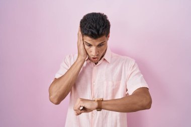 Pembe arka planda duran genç İspanyol adam saate bakıyor. Endişeli, geç kalmaktan korkuyor. 