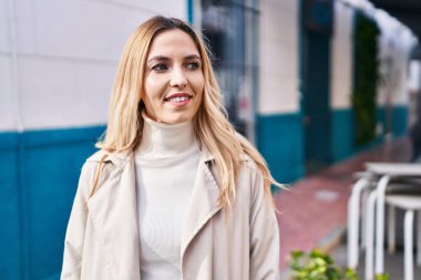 Young blonde woman smiling confident looking to the side at street