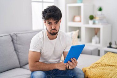 Sakallı İspanyol bir adam kanepeye oturmuş komik suratıyla yanaklarını şişiriyor. Havayla şişmiş ağız, çılgın bir ifade.. 