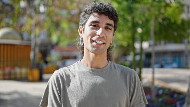 Parkta kendinden emin gülümseyen İspanyol genç adam.