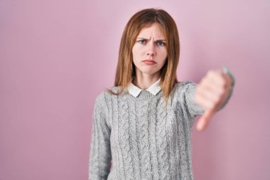 Pembe arka planda duran güzel bir kadın mutsuz ve kızgın görünüyor. Reddedilmiş ve olumsuz bir hareket sergiliyor. kötü ifade. 