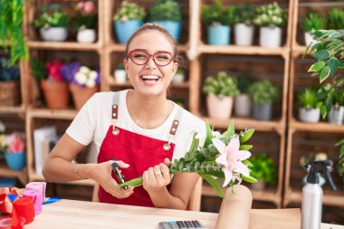 Young beautiful hispanic woman florist cutting stem at florist