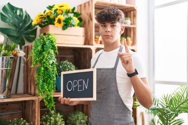 Çiçekçide çalışan İspanyol genç elinde açık tabela tutarken bir fikir ya da soru işareti görünce şaşırdı. 
