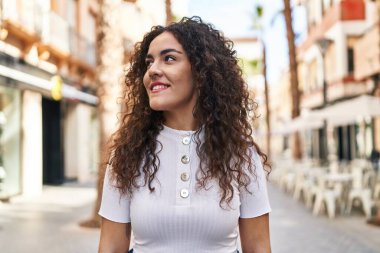 Young beautiful hispanic woman smiling confident looking to the side at street