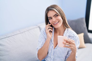 Kahve içen ve akıllı telefondan konuşan genç bir kadın.