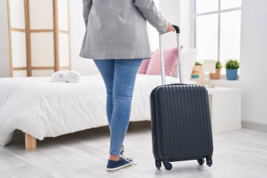 Young hispanic woman business worker holding suitcase walking at hotel room