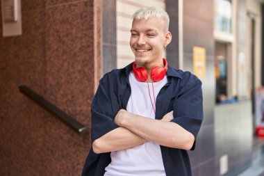 Young caucasian man smiling confident standing with arms crossed gesture at street