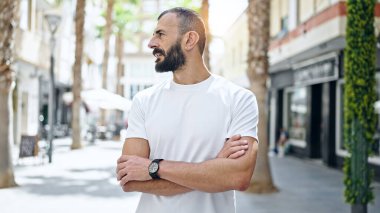 Kollarını kavuşturup caddeye bakan İspanyol genç adam.