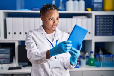 Örgü ören Afrikalı Amerikalı bir kadın bilim adamı laboratuarında çalışıyor. Tabletle video görüşmesi yapıyor. Ağzını açıp şaşkınlık ve şaşkınlık içinde konuşuyor. 