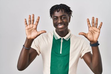 Münzevi arka planda duran Afrikalı adam on numarayı gösterip işaret ederken kendinden emin ve mutlu gülümsüyor.. 