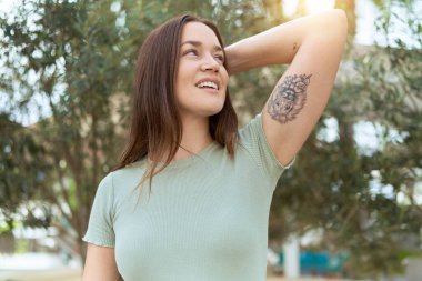 Genç, güzel bir kadın, gülümsüyor. Parkta elleri ve ayakları üzerinde rahatlamış.