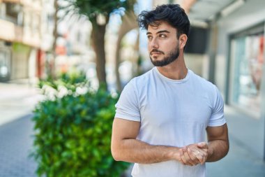 Young hispanic man with relaxed expression standing at street