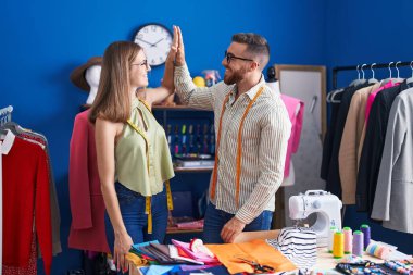 Erkek ve kadın terziler giyim fabrikasında elleri havada beşlik çakıyor.