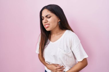 Genç Arap kadın, midesi üstünde pembe arka planda duruyor çünkü hazımsızlık, acı verici bir hastalık kendini iyi hissetmiyor. Ağrı kavramı. 