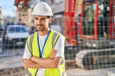 Young hispanic man architect smiling confident standing with arms crossed gesture at street