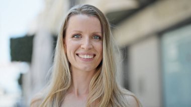 Sokakta kendine güvenen genç sarışın kadın gülümsüyor