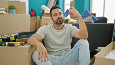 Yeni bir evde kredi kartı tutan genç bir İspanyol.