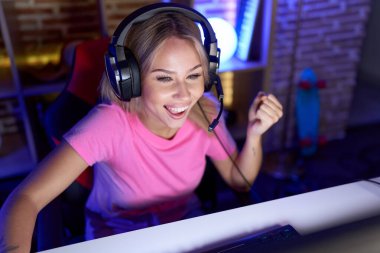 Genç sarışın kadın oyuncu oyun odasında video oyunu oynuyordu.