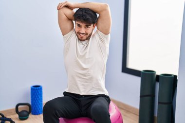 Genç İspanyol adam gülümsüyor spor merkezinde esniyor.