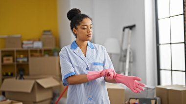 Afro-Amerikalı kadın temiz profesyonel. Yeni evinde eldiven giyiyor.