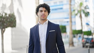 Sokakta rahat bir ifadeyle duran genç Latin iş adamı.