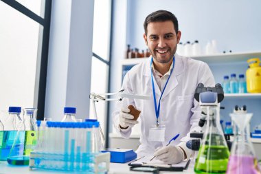 Genç İspanyol bilim adamı elinde değerli taşla laboratuardaki belgeye yazı yazıyor.