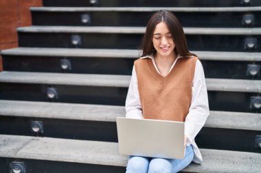 Sokağın merdivenlerinde dizüstü bilgisayar kullanan güzel bir İspanyol kadın.