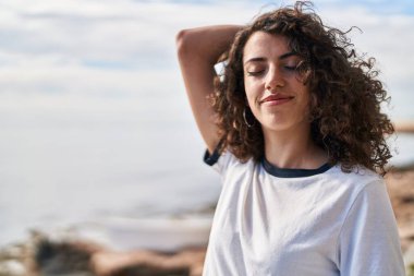 Genç İspanyol kadın gülümsüyor. Kendine güveni tam, deniz kenarında başı rahat.