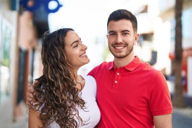 Young hispanic couple smiling confident hugging each other at street