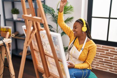 Sanat stüdyosunda müzik dinleyen Afrikalı Amerikalı kadın sanatçı.