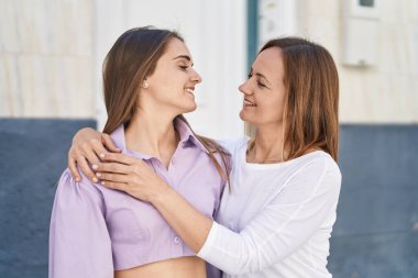 İki kadın anne ve kızı sokakta birbirlerine sarılıyorlar.