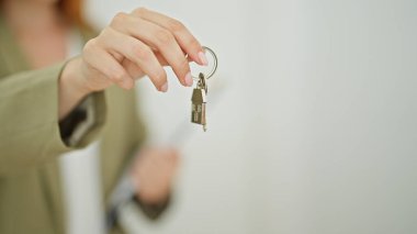 Genç kızıl saçlı kadın emlakçı elinde anahtarlar var.