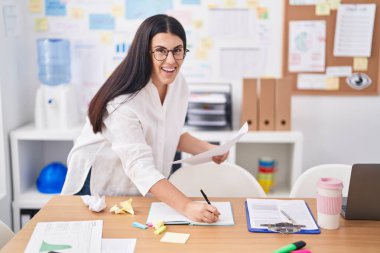 Genç, güzel İspanyol iş kadını. Not defterine yazı yazıyor. Ofiste evrakları tutuyor.