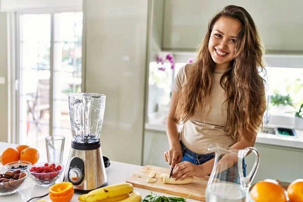 年轻美丽的恐慌女人在厨房用搅拌机切香蕉准备蔬菜冰沙 — 图库照片