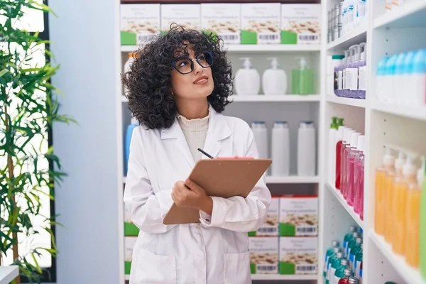 Young middle eastern woman pharmacist writing on document at pharmacy