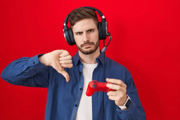 怒っている顔を持つコントローラーを保持するビデオゲームをプレイするヒスパニック男性 否定的なサインは 親指の下に嫌いを示しています 拒絶概念 — ストック写真