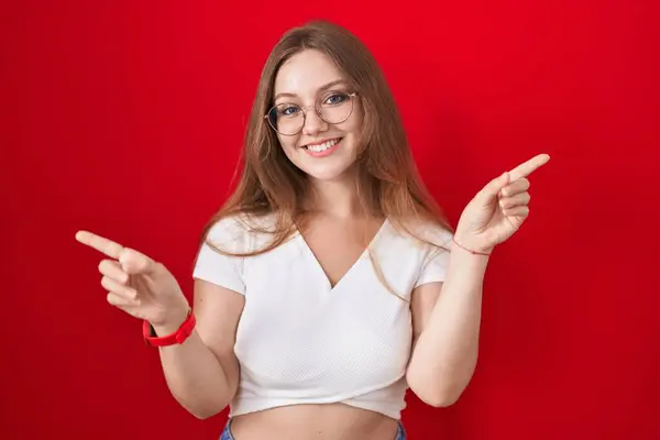 Jeune Femme Caucasienne Debout Sur Fond Rouge Souriant Confiant Pointant — Photo