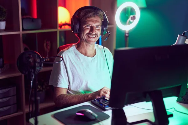 Young blond man streamer playing video game using computer at gaming room