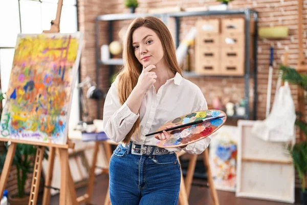 Young Caucasian Woman Art Studio Holding Palette Serious Face Thinking — Stock Photo, Image