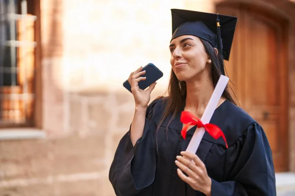 Young Hispanic Woman Wearing Graduated Uniform Holding Diploma Hearing Audio — Foto de Stock