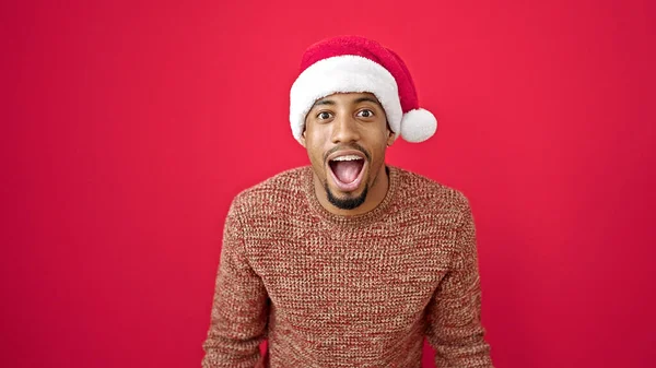 Hombre Afroamericano Expresión Sorpresa Usando Sombrero Navidad Sobre Fondo Rojo — Foto de Stock