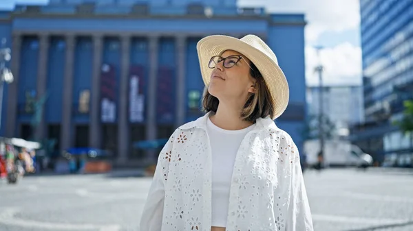 ノーベル賞ビルで夏の帽子をかぶっている側に自信を持って笑っている美しい若いヒスパニックの女性 — ストック写真