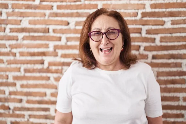 Mujer Mayor Con Gafas Pie Sobre Ladrillos Parpadeando Mirando Cámara —  Fotos de Stock